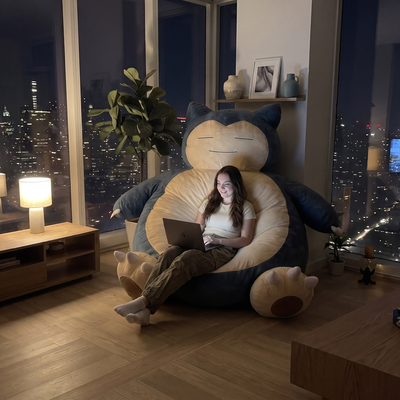 Woman relaxing with a laptop on the SnorCozy bean bag at night